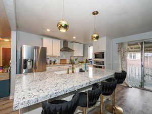 Kitchen with white cabinets, appliances with stainless steel finishes, a kitchen bar, dark wood-style floors, and recessed lighting