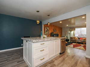 Kitchen featuring white cabinetry, decorative light fixtures, dark wood-style flooring, and light stone counters