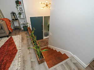Staircase with wood finished floors, a chandelier, and a textured wall