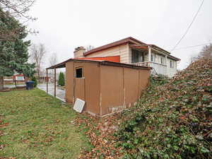 View of side of property with a yard, a chimney, and a balcony
