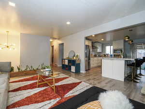 Living room with a chandelier, light wood-type flooring, and recessed lighting
