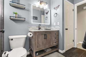 Full bath with vanity and dark wood-style flooring