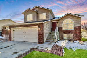 View of front of property with brick siding, driveway, an attached garage, and roof with shingles