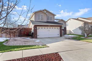 Traditional home with brick siding, roof with shingles, driveway, and a garage