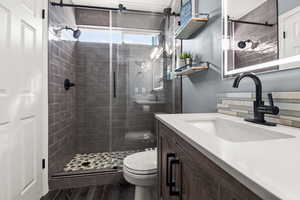 Bathroom with vanity, a shower stall, and dark wood-style flooring