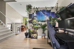 Living area with wood finished floors, stairway, an office area, and a towering ceiling