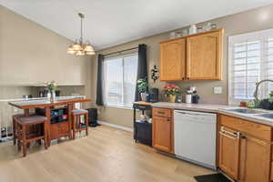 Kitchen featuring dishwasher, light countertops, light wood-style floors, hanging light fixtures, and vaulted ceiling