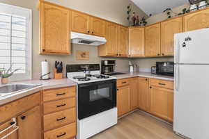Kitchen featuring range with electric stovetop, freestanding refrigerator, under cabinet range hood, light countertops, and black microwave