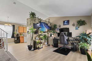 Home office with lofted ceiling, light wood-style floors, and a chandelier