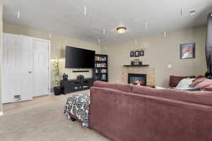 Living room featuring a tile fireplace, carpet, and a textured ceiling