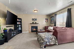 Carpeted living room featuring a tile fireplace and a textured ceiling