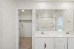 **DISCALIMER** Interior options may vary.Bathroom with a walk in closet, a stall shower, double vanity, and light carpet
