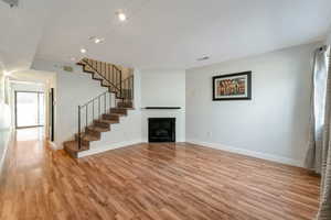 Unfurnished living room with track lighting, a fireplace, light wood-type flooring, and stairway