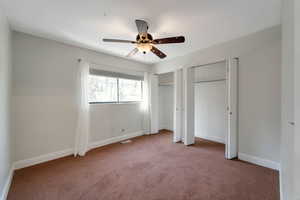 Unfurnished bedroom with multiple closets, carpet, and a ceiling fan