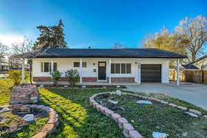 Ranch-style house featuring covered porch, concrete driveway, a garage, a front lawn, and brick siding