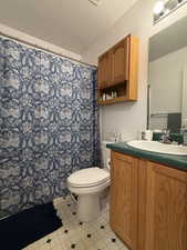 Full bath featuring vanity, a shower with curtain, a textured ceiling, and light tile patterned floors