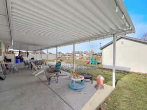Fenced backyard with an outdoor fire pit, a patio area, a residential view, a shed, and a playground