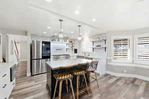Kitchen with appliances with stainless steel finishes, pendant lighting, white cabinets, a breakfast bar, and recessed lighting