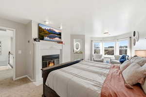 Bedroom with a tile fireplace and light colored carpet