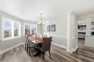 Dining area featuring decorative columns, light wood-style floors, and a chandelier