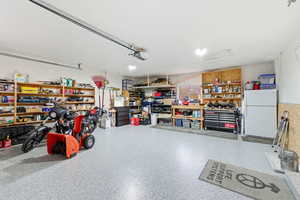 Garage featuring a workshop area and freestanding refrigerator