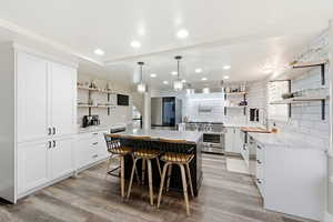 Kitchen with open shelves, white cabinets, decorative light fixtures, recessed lighting, and appliances with stainless steel finishes
