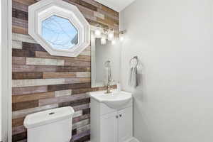 Half bath featuring wood walls and vanity