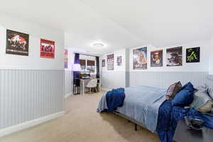 Carpeted bedroom featuring a desk and baseboards