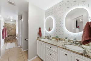 Full bath featuring double vanity and light tile patterned floors