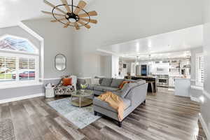 Living area featuring light wood-style floors, a ceiling fan, and high vaulted ceiling