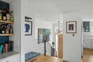 Hall with light wood finished floors, a chandelier, and an upstairs landing