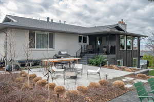 Back of house featuring a patio area, board and batten siding, a shingled roof, and a chimney
