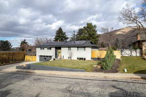Split foyer home featuring solar panels, an attached garage, concrete driveway, and a metal roof