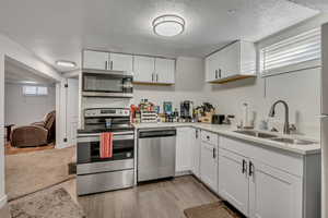 Kitchen with stainless steel appliances, healthy amount of natural light, white cabinetry, and a textured ceiling