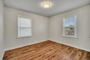 Unfurnished room featuring wood finished floors, plenty of natural light, and a textured ceiling