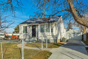 View of front of property featuring a fenced front yard, a detached garage, a gate, an outdoor structure, and concrete driveway