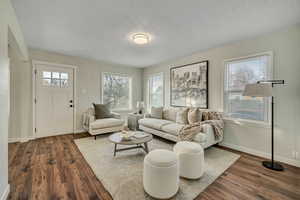 Living area featuring dark wood-style floors, plenty of natural light, and a textured ceiling