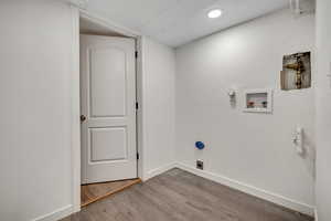 Laundry room with a textured wall, wood finished floors, washer hookup, and gas dryer hookup
