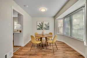 Dining area with light wood-type flooring and a textured ceiling