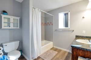 Bathroom with shower / bath combo with shower curtain, vanity, and light wood-style floors