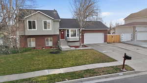 Tri-level home with brick siding, driveway, a gate, an attached garage, and roof with shingles