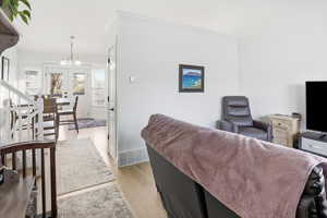 Living room with light wood finished floors, a chandelier, stairs, and french doors