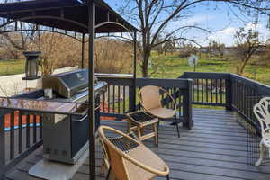Wooden deck featuring a grill and a gazebo