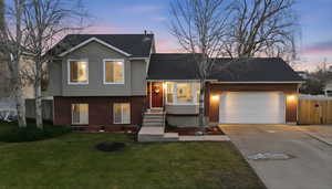 Tri-level home with brick siding, driveway, a garage, and a shingled roof