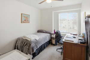 Bedroom featuring an office area, light colored carpet, and ceiling fan