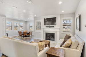 Living area with a glass covered fireplace, recessed lighting, healthy amount of natural light, and wood finished floors