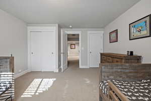 Bedroom with light colored carpet, multiple closets, and a textured ceiling
