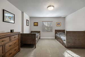 Bedroom featuring light carpet and a textured ceiling