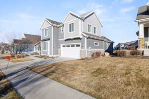 View of home's exterior with board and batten siding, concrete driveway, an attached garage, a yard, and a residential view