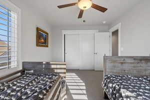 Carpeted bedroom with a closet and ceiling fan